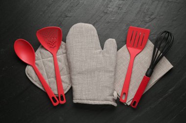 Gri fırın eldiveni ve diğer mutfak gereçleri koyu dokulu masa üzerinde, düz yatıyordu.