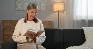 Evdeki kanepede kitap okuyan güzel bir son sınıf öğrencisi.