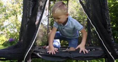 Mutlu küçük çocuklar siyah trambolinde zıplıyorlar, kamera yukarı çıkıyor.