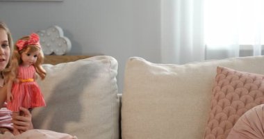 Hayaller gerçek olur. Evdeki kanepede güzel bir bebeği olan sevimli küçük kız, sola hareket eden kamera.