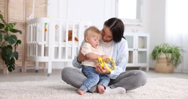 Anne ve küçük tatlı çocuğu bebek odasında oyuncaklarla oynuyorlar.