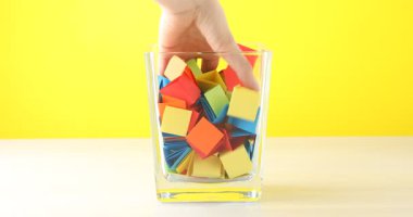 Ahşap masadaki cam kavanozdan açık mavi kağıt parçası alan kadın, yakın plan.