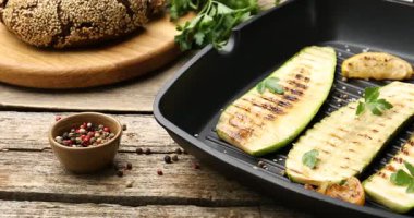 Baharatlı lezzetli ızgara kabak dilimleri ve ahşap masada limon, yakın plan. Kamera sağa hareket ediyor