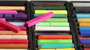 Masada renkli tebeşirli pastel boya seti, yakın plan. Kamera sola hareket ediyor