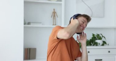 Mutlu adam kulaklıkla müzik dinliyor ve evde dans ediyor.