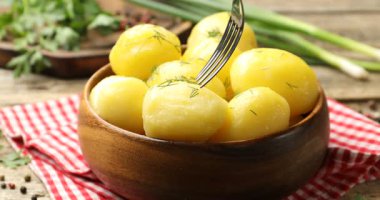 Tahta masada çatalla kaynamış patatesleri yakın plan çekiyoruz.