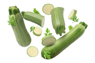 Beyaz arka plana düşen taze kabak ve maydanoz parçaları.