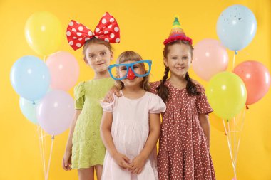 Doğum günü kutlaması. Turuncu arka planda balonları olan çocuklar.