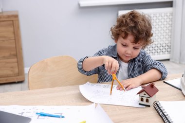 Meslek seçimi. Masada bölme ve mühendislik çizimi yapan küçük çocuk.