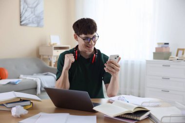 İyi bir sınav sonucunu kutlayan mutlu öğrenci içeride masada.