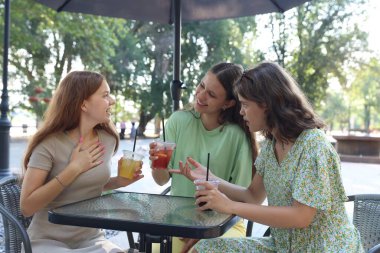 Arkadaşlar açık kafede içeceklerin tadını çıkarıyorlar.