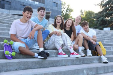 Bir grup mutlu genç arkadaş dışarıda birlikte vakit geçiriyorlar.