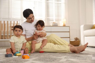 Annem evde sevimli küçük ikizleri ve oyuncaklarıyla