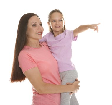 Kızı beyaz arka planda annesine bir şey gösteriyor.