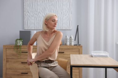 Ofiste sandalyeye uzanan olgun bir kadın.