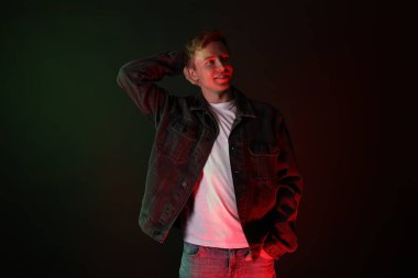 Siyah arka planda neon ışıklar altında gülümseyen adam.