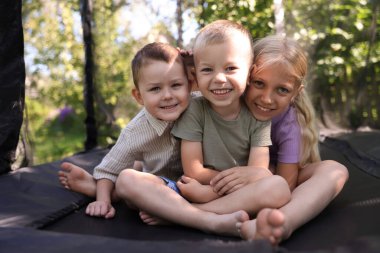 Siyah trambolinde poz veren küçük mutlu arkadaşlar.