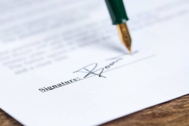 Tahta masadaki dolmakalemle noter belgesi imzalama, seçici odak