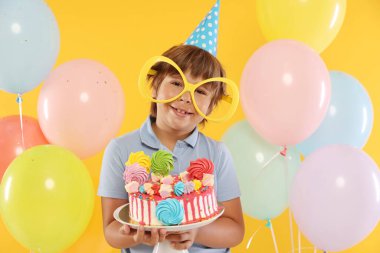 Doğum günü kutlaması. Tatlı ve turuncu arka planda balonları olan tatlı bir çocuk.