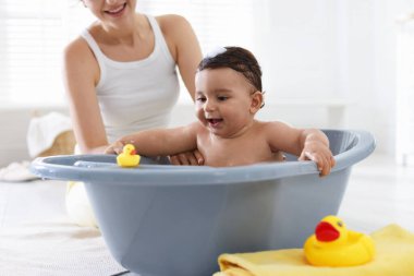 Anne küçük bebeğini evde yıkıyor, yakın plan.