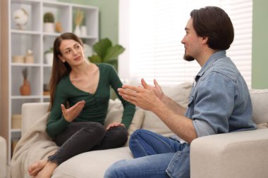 Kadın ve erkek evdeki kanepede konuşuyor.