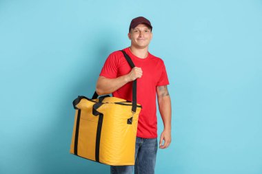 Açık mavi arka planda termo çantalı bir kurye. Yemek dağıtım servisi.