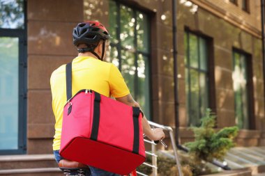 Termo çantalı kurye dışarıda bisiklet sürüyor, mesaj için yer var. Yemek dağıtım servisi.