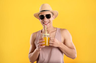 Meyve suyu ve turuncu arka planda saman içen adam.