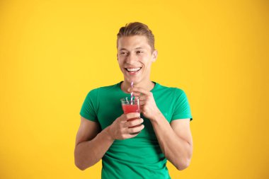 Meyve suyu ve turuncu arka planda saman içen adam.