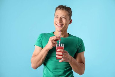 Meyve suyu ve açık mavi arka planda saman içen bir adam.