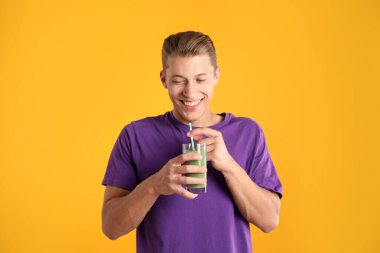 Meyve suyu ve turuncu arka planda saman içen adam.