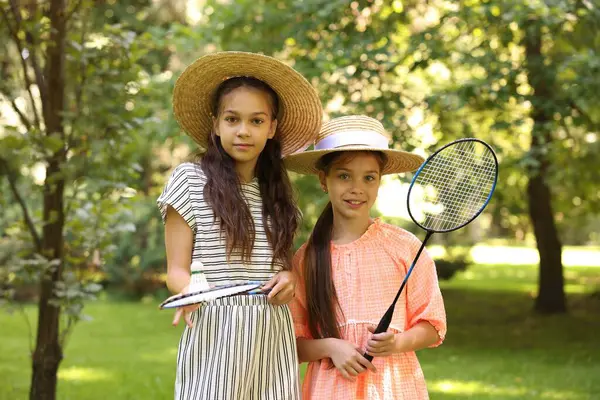Badminton raketleri ve parkta küçük bir pikapla gülümseyen kızların portresi.