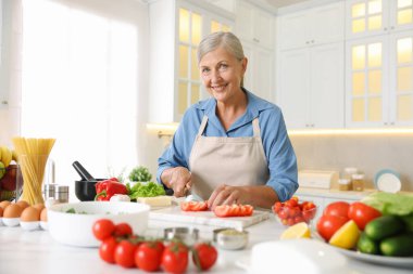 Mutfaktaki masada yemek pişiren son sınıf kadını.