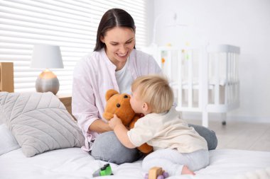 Anne, küçük bebeği ve oyuncağıyla odada.