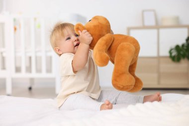 Yatakta oyuncaklarla oynayan tatlı bir bebek.