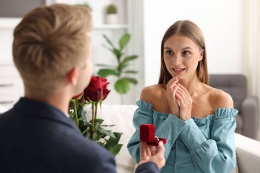 Nişan yüzüğü ve gül buketi olan bir adam mutlu kız arkadaşına evlenme teklif ediyor.