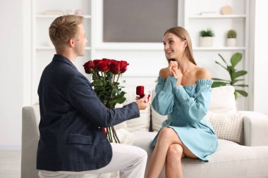 Nişan yüzüğü ve gül buketi olan bir adam mutlu kız arkadaşına evlenme teklif ediyor.