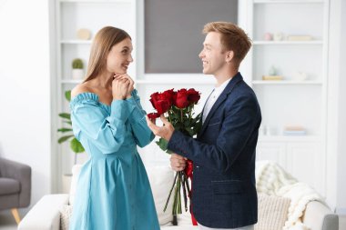 Nişan yüzüğü ve gül buketi olan bir adam mutlu kız arkadaşına evlenme teklif ediyor.