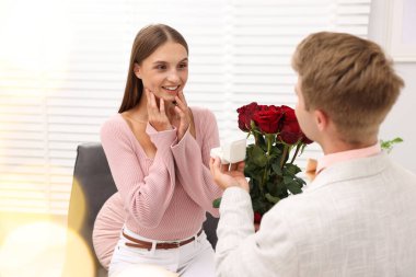 Nişan yüzüğü ve gül buketi olan bir adam mutlu kız arkadaşına evlenme teklif ediyor. Bokeh etkisi