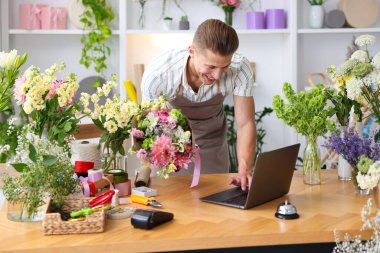 Dükkandaki ahşap masada çalışan bir buket çiçekli profesyonel çiçekçi.