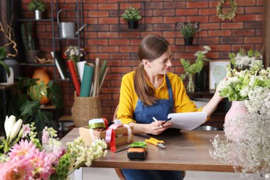 Dükkandaki ahşap masada çalışan profesyonel bir çiçekçi.