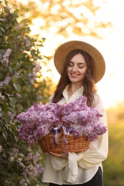 Gülen bir kadın ve açık havada bir sepet leylak çiçeği.