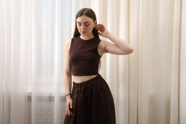 Evdeki pencerenin yanında poz veren güzel kadın.