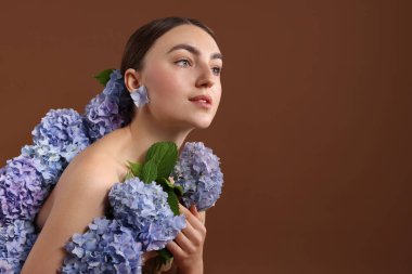 Kahverengi arka planda hortensiya çiçekleri olan güzel bir genç kadın. Metin için boşluk