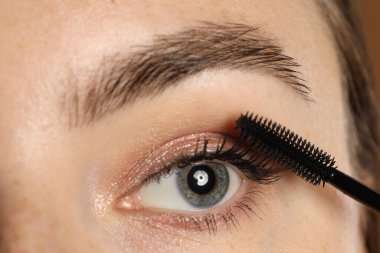 Bir kadın kirpiklerine rimel sürüyor, yakın plan.