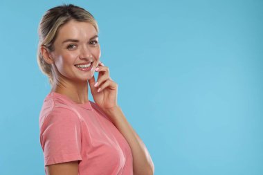 Açık mavi arka planda sağlıklı dişleri olan güzel bir kadın. Metin için boşluk