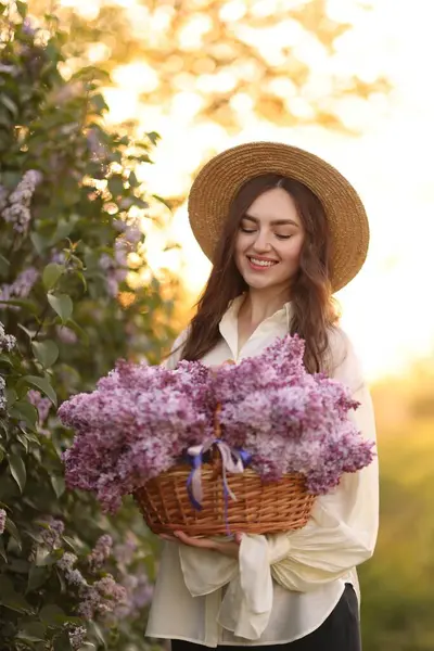 Gülen bir kadın ve açık havada bir sepet leylak çiçeği.