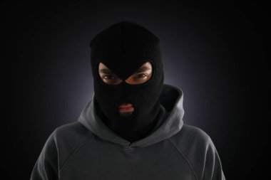 Karanlık arka planda maskeli bir suçlu.