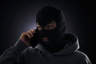 Maskeli bir suçlu telefonda karanlık geçmişiyle konuşuyor.