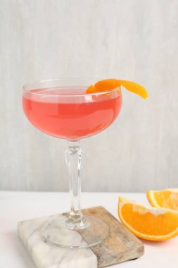 Martini kokteyli, garnitür ve portakal dilimleri beyaz masada, yakın plan.